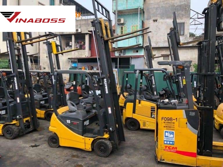  Cận cảnh một kỹ thuật viên Vinaboss đang siết một con ốc quan trọng trên động cơ xe nâng, mồ hôi lấm tấm trên trán, thể hiện sự tập trung cao độ và gấp rút.]